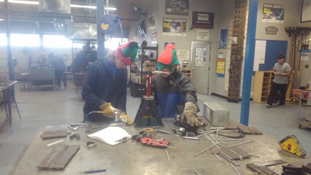 Students work in elf hats in a machine shop