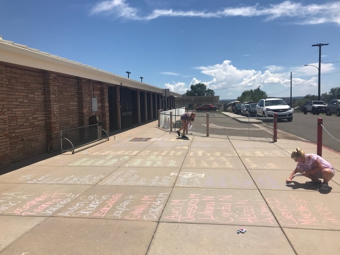 Kids writing on the sidewalk with chalk.