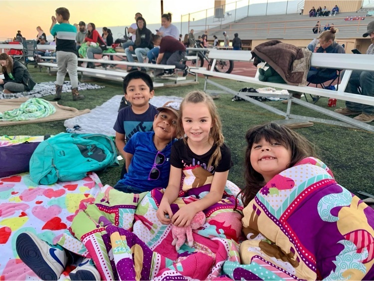 kindergartners enjoying movie night on the football field.
